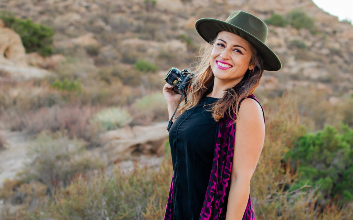 Debra Morrison holds a camera and smiles in the desert