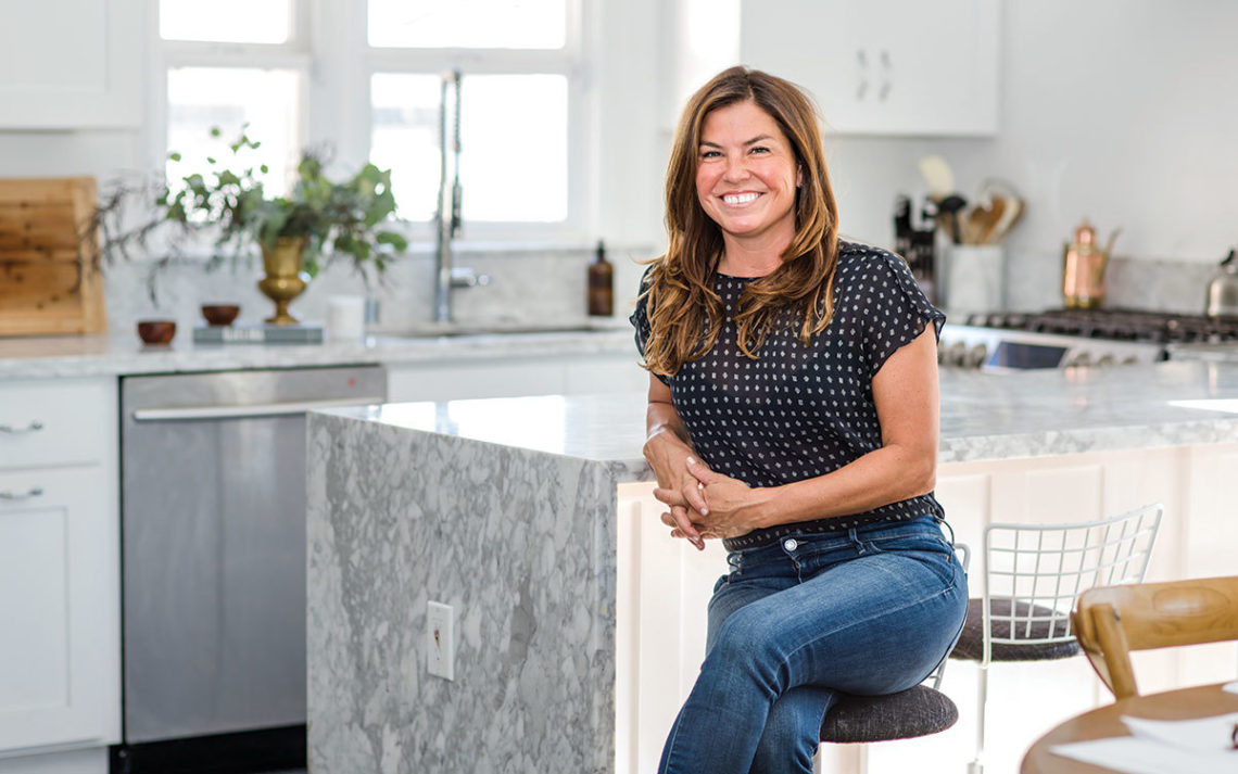 Jenny Rybek, owner of Live Simple, sits in a bright, organized kitchen
