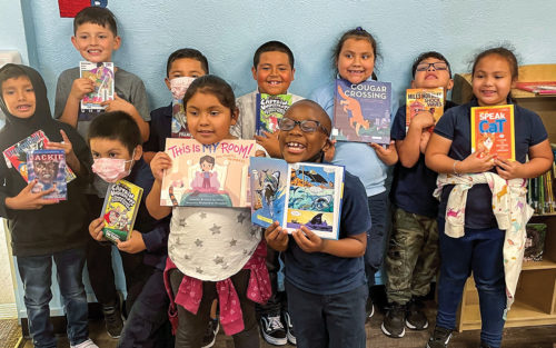 Young children smiling, holding books supplied by Access Books.
