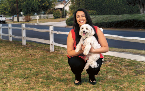 Madison of Dog Sitting Company holding a dog in a front yard