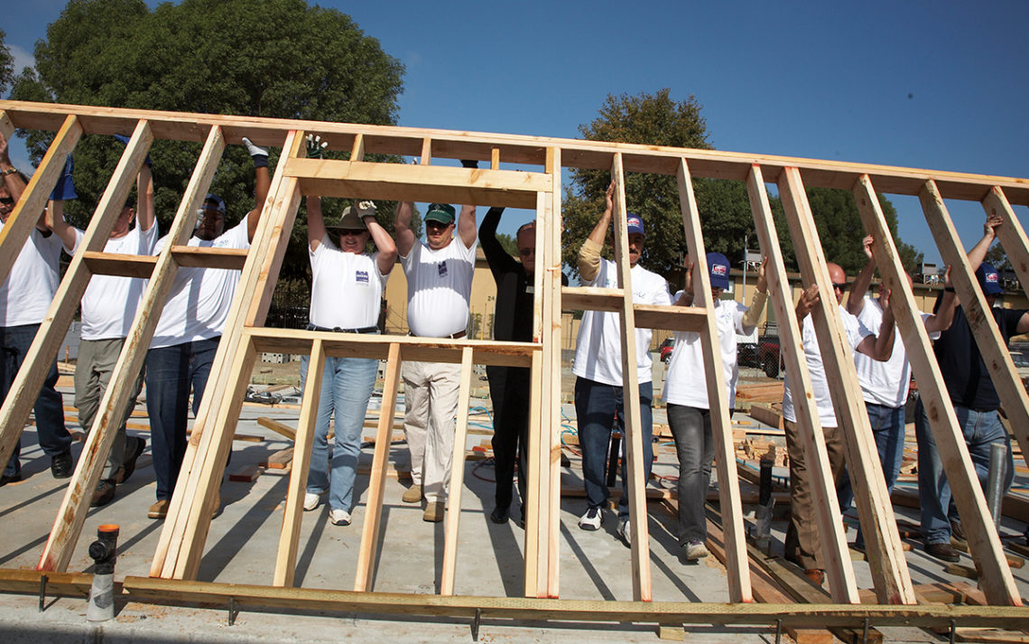 Volunteers for Homes4Families braise a wall together for a home